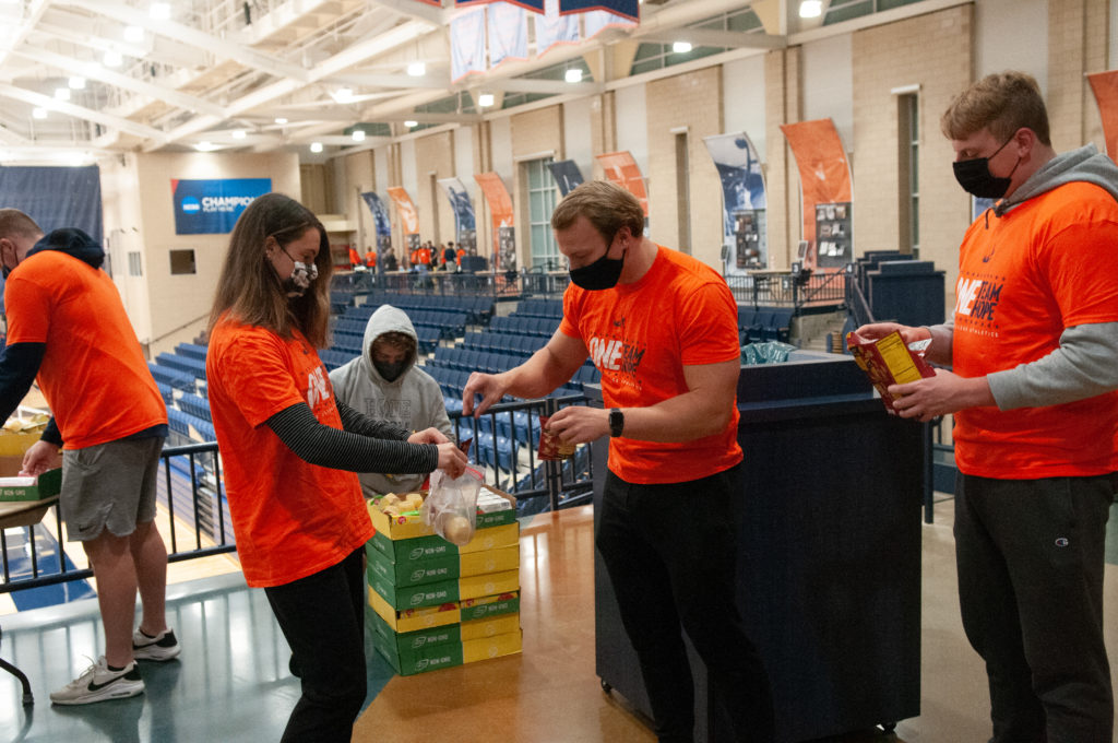 Five Hope College student-athletes pack granola bars, crackers, apple sauce and fruit snacks in a Ziploc bags at DeVos Fieldhouse.