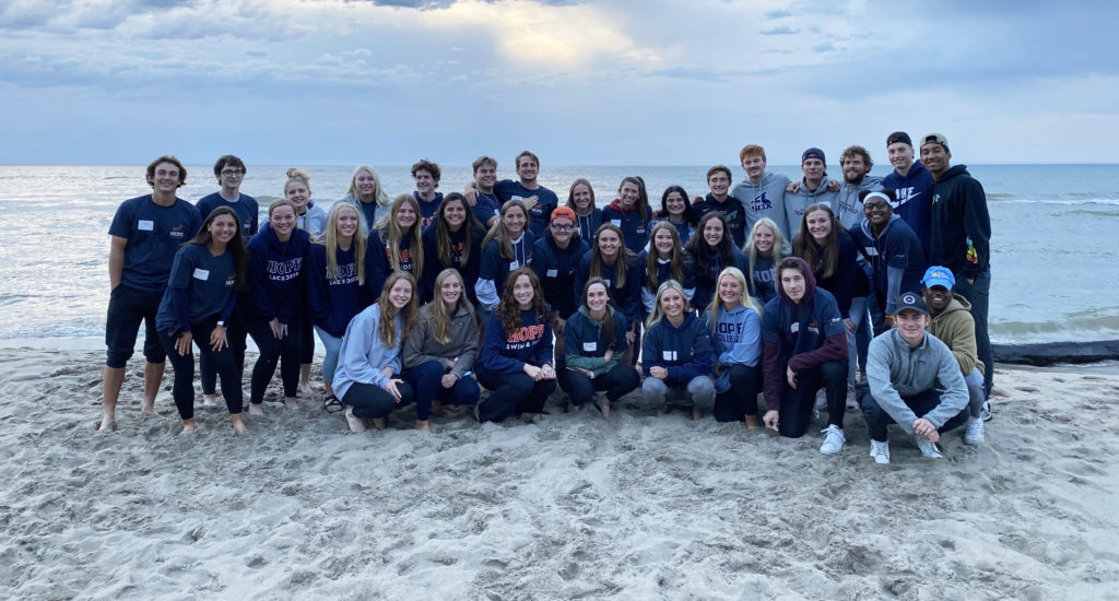 40 Hope student-athletes poses for a group photo on the shores of Lake Michigan.