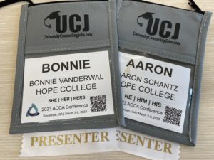 Two paper name tags--one for Bonnie VanderWal and one for Aaron Schantz--are side-by-side.  Each one is in a gray name tag holder that goes around a person's neck and each has a white ribbon attached to the bottom that says "Presenter" in gold.