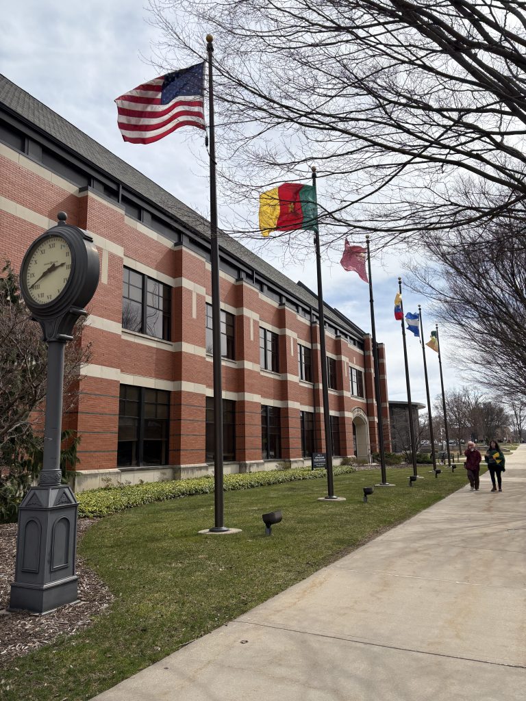 View outside the Martha Miller Center featuring flags and 2 students walking