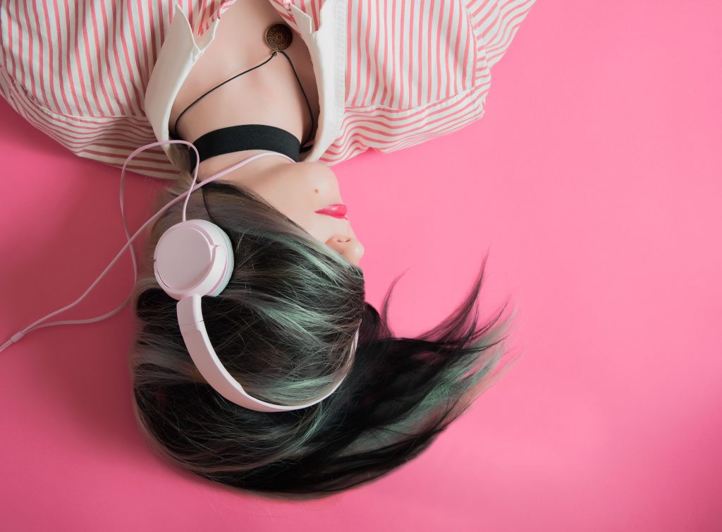 Upside-down image of a woman with green hair listening to headphones.