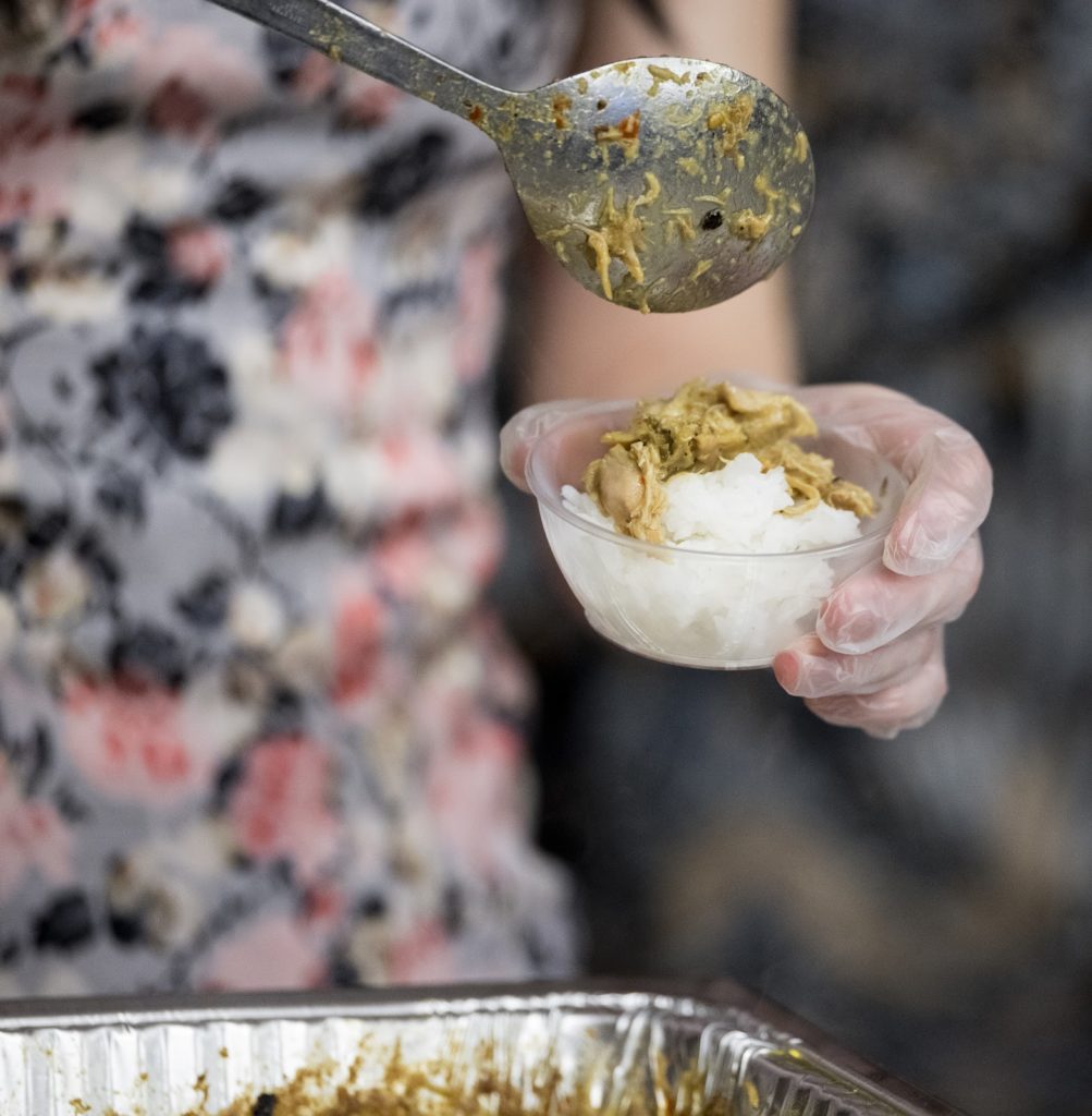 A person dishes ayam (chicken) gulai into a small bowl