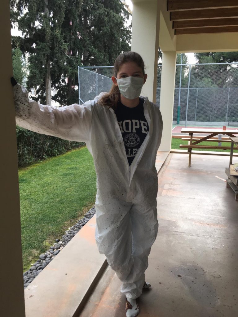 A photo of me wearing a surgical mask and full body clean suit so that I won't cover my clothing with ash while sorting through cremated pig remains.