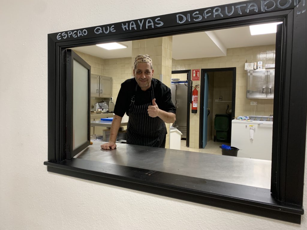 Our chef, Javi, at the kitchen window which reads “We hope you’ve enjoyed!” Javi cooks us 14 hot meals a week.
