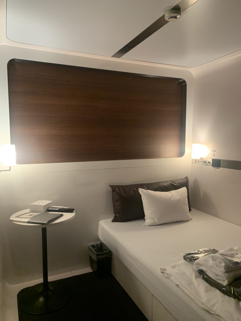 cabin at haneda airport, featuring a bed, side table, and various amenities.