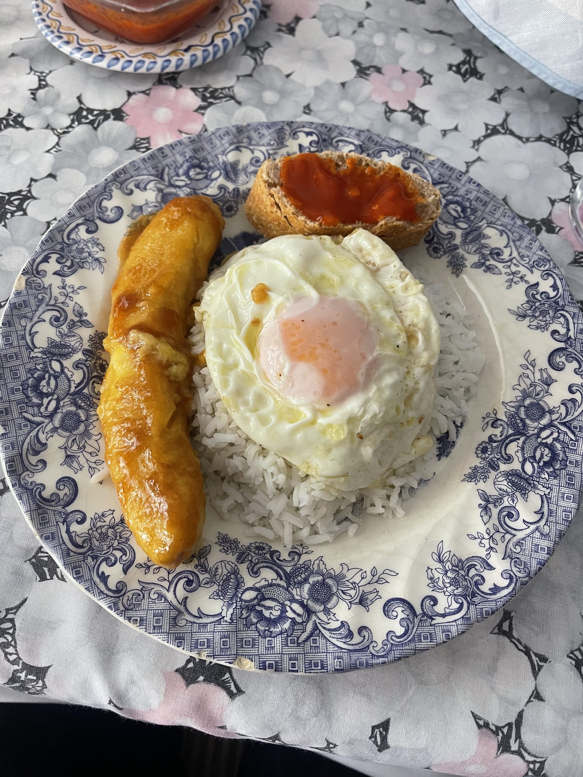 A picture of a plate with rice, a fried egg, and a plantain.