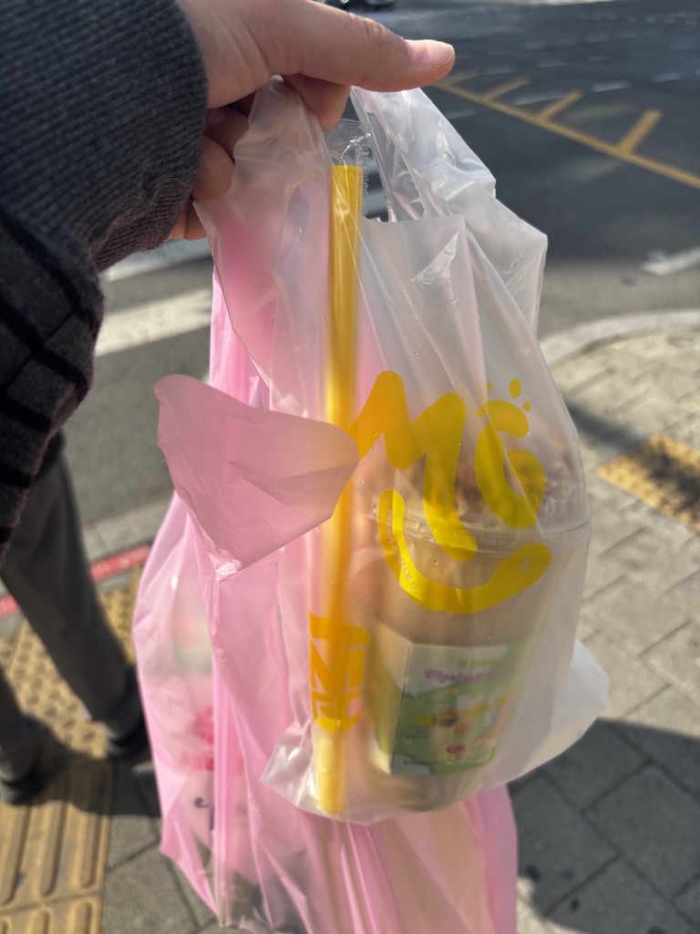 A clear plastic bag containing a coffee cup with a yellow straw and another pink bag.