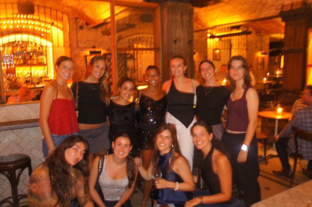 A group of study abroad friends posing together inside a warmly lit restaurant after sharing a meal.