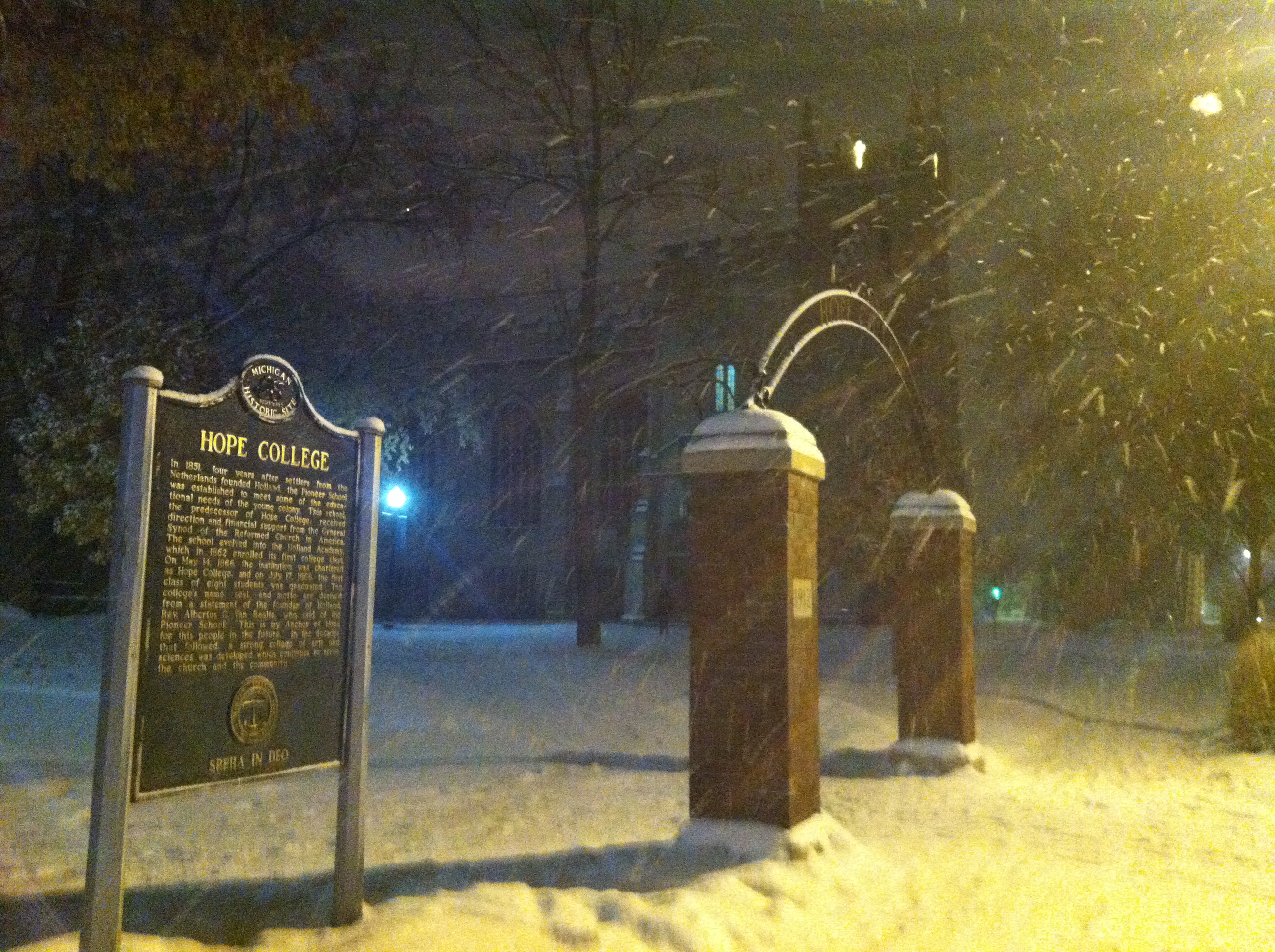 Snow swirling past the Hope College arch and sign