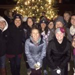 A group of college students in front of a Christmas tree