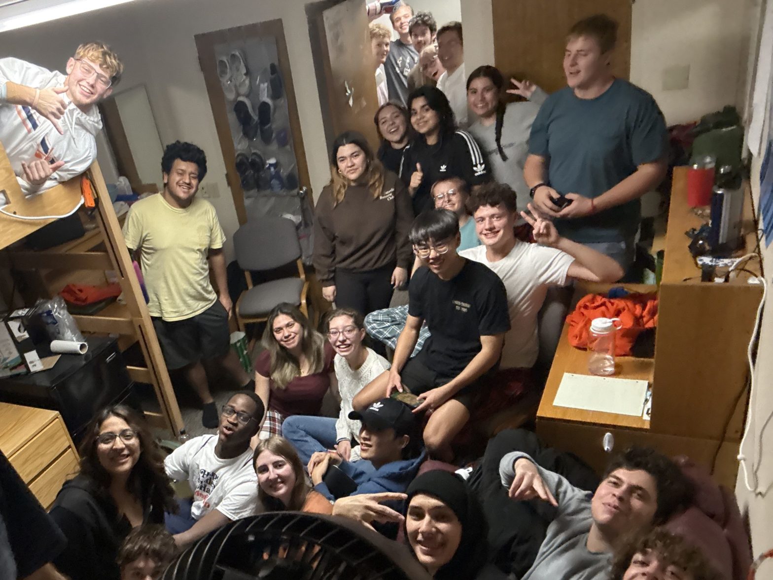 A group of several students gather for a photog in a dorm room in Scott Hall